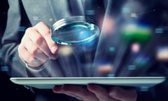 Businessman examines a tablet with a magnifying glass.