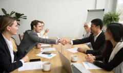 Diverse businessmen shaking hands after signing contracts at group multiracial meeting, african and caucasian partners in suits handshaking promising good deal after successful negotiations concept