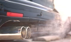 Close up of smoky dual exhaust pipes from a starting diesel car - emissions scandal.