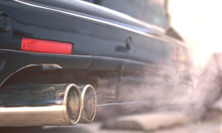 Close up of smoky dual exhaust pipes from a starting diesel car - emissions scandal.