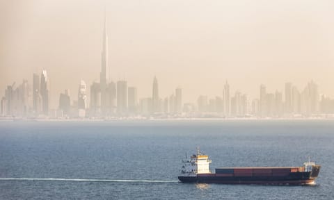 Cargo container ship and Dubai skyscrapers on a background