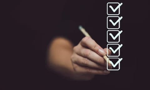 Marking on checklist box isolated on black background. Checklist concept. Hand holding a pencil and checklist isolated on black background with copy