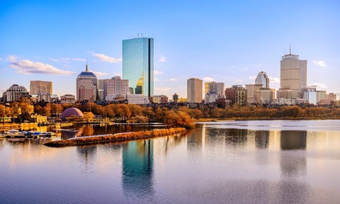 Boston City Skyline over the Charles River in Massachusetts, USA. A tranquil riverscape of Back Bay with golden illuminated wintery foliage in New England.