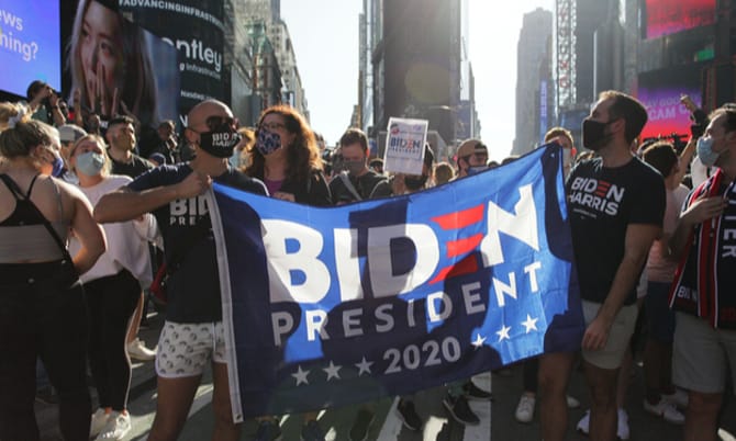 Revellers in Times Square hold up a Biden Harris 2020 flag to celebrate after Joe Biden's victory over Donald Trump in the 2020 presidential election